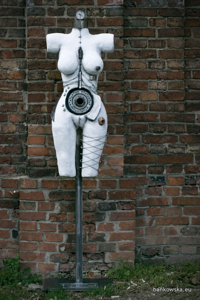 A contemporary cyberpunk sculpture presenting the female body as a site of tension between flesh, data, and machine.